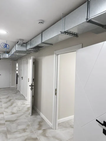 Besa Diş Kliniği alt kat koridorunda askılarla sabitlenen dikdörtgen hava kanalı ve oda kapıları.