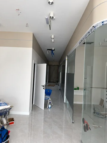 Besa Diş Kliniği uygulama aşamasındaki koridorda cam bölmeler, açık kapı ve tavan yerleşimi.