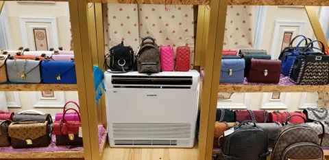 Sultanahmet Bazaar'ın çanta rafları altında bulunan beyaz konsol tipi klima ve ahşap teşhir düzeni.